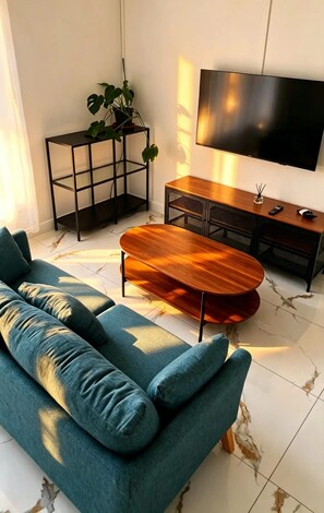 Un salon moderne avec un canapé, une table basse, un téléviseur et une plante.