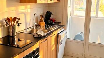 Eine moderne Küche mit Holzschränken, einer schwarzen Arbeitsplatte, einem eingebauten Backofen und einem Geschirrspüler.