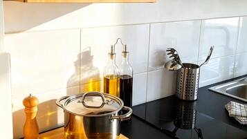 Une cuisine avec des meubles de rangement en bois, un plan de travail noir, une cuisinière et divers ustensiles de cuisine.