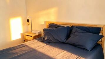 Ein Schlafzimmer mit einem Bett, einem Holzkopfteil, einem Nachttisch, einer Lampe und einem gerahmten Bild an der Wand.