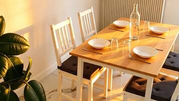 Un coin repas avec une table en bois, des chaises blanches et une plante en pot.