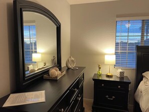 A bedroom with a large mirror, a dresser, a bedside table with lamps, and a window with blinds. - Pet Friendly-Priv. Pool-King Suite-Golf Nearby (San Tan Valley)
