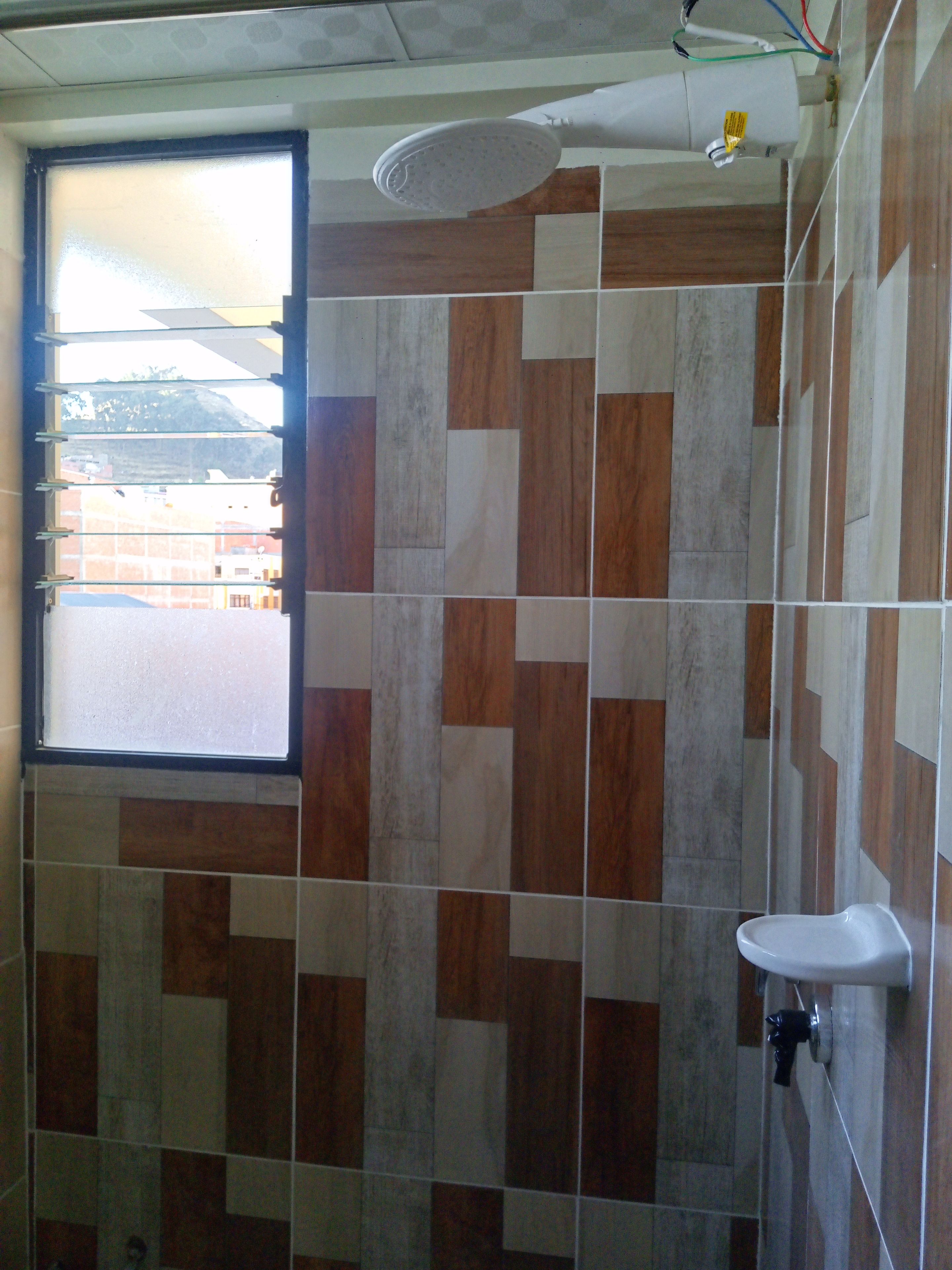 Un baño con ventana, ducha y lavamanos.