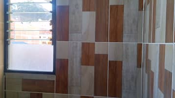Un baño con ventana, ducha y lavamanos.