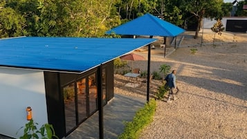 A modern outdoor area with a covered seating area, a gravel path, and a building with large windows.