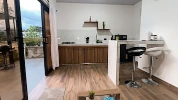 Et moderne køkken med spiseområde, et sofabord med en bog og udsigt gennem en glasdør.