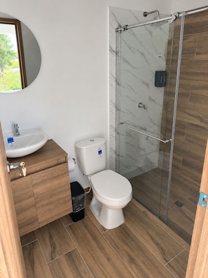 Un baño con inodoro, lavamanos y cabina de ducha de vidrio.