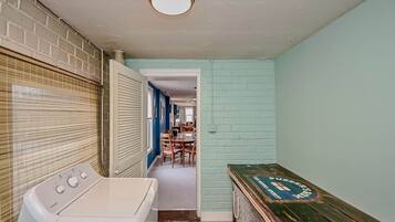A laundry area with a washing machine, a drying rack, and a wooden bench with a vintage design.