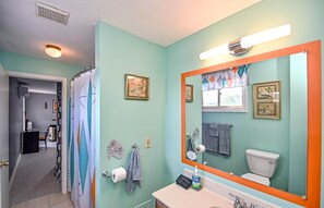 Een badkamer met een grote spiegel, toilet en wastafel. Handdoeken en een douchegordijn zijn zichtbaar.