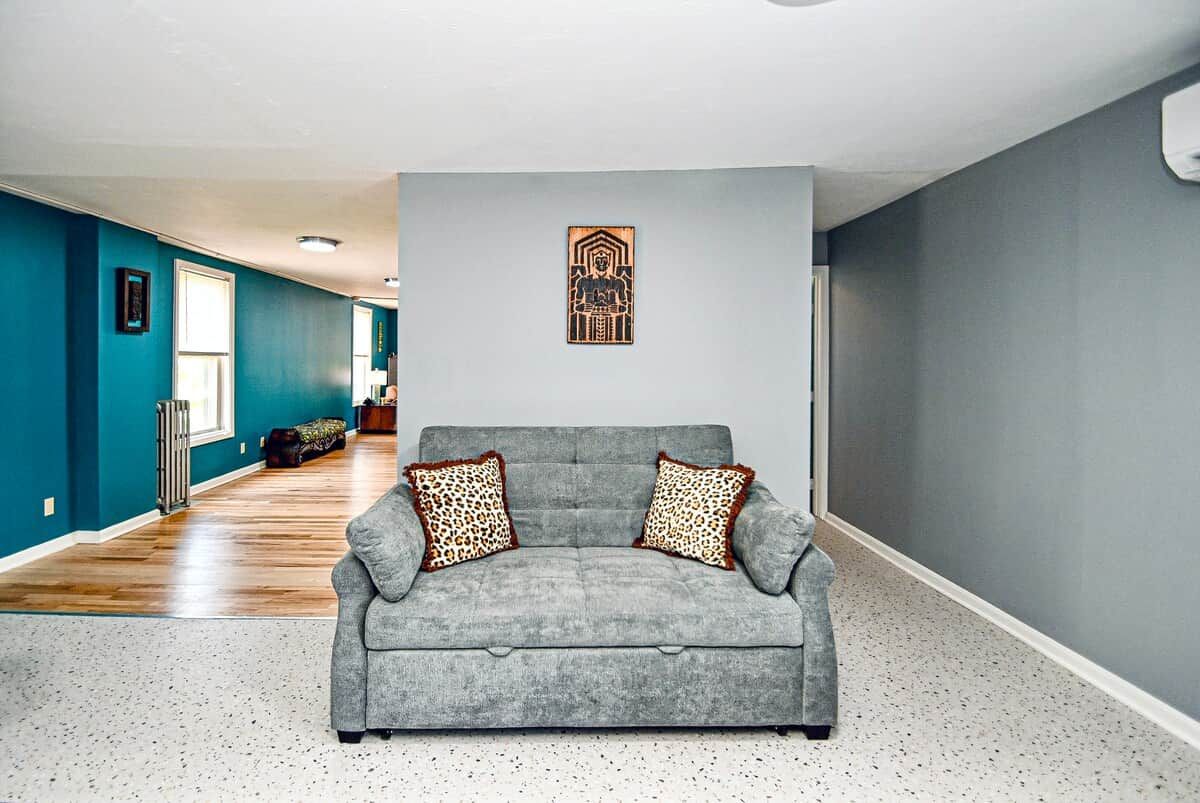 A living room with a grey sofa, leopard print cushions, and a wall-mounted artwork.