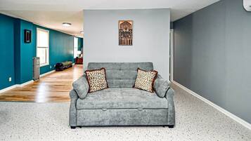 A living room with a grey sofa, leopard print cushions, and a wall-mounted artwork.