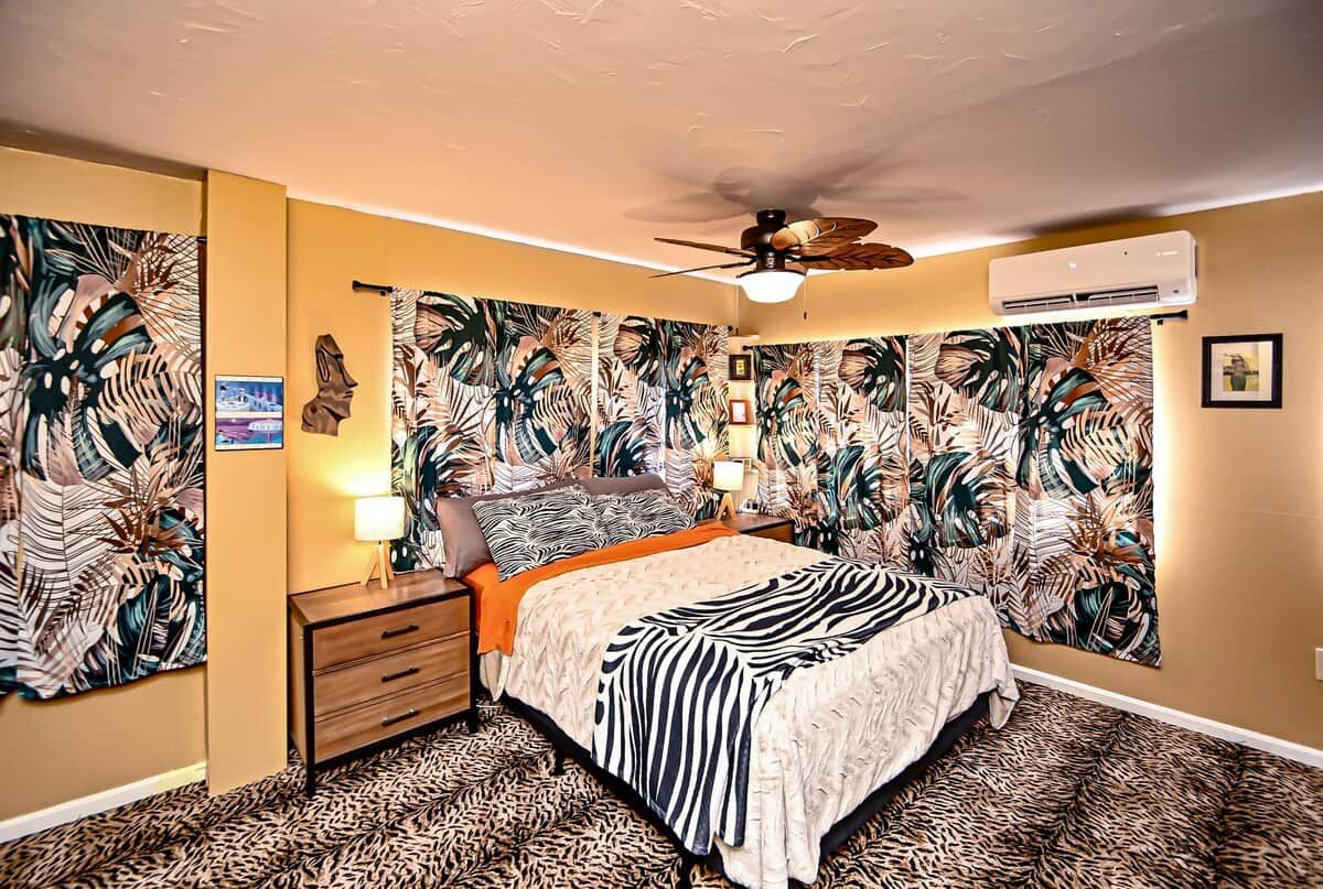 A bedroom with a bed, a nightstand, a ceiling fan, and wall art.