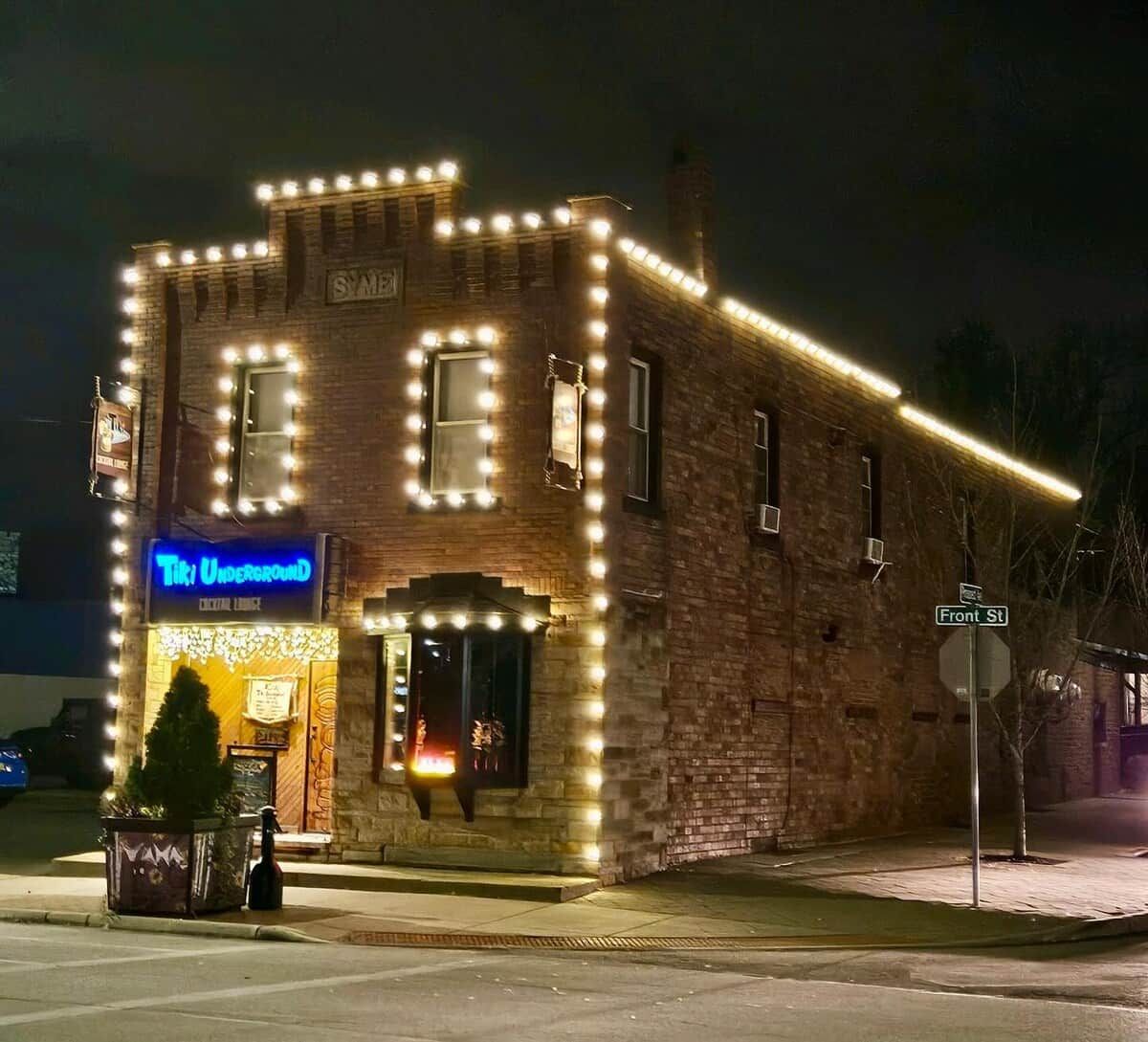 A brick building with a neon sign for 'Tiki Underground' and a street sign for 'Front St.'