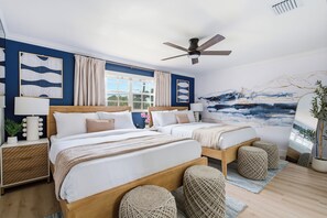 A hotel room with two beds, a ceiling fan, a large window with curtains, a painting on the wall, and a potted plant. - The Privateer, Cold Plunge, Hot Tub, Sauna + Games (Tampa)