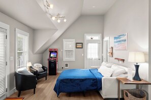 A bedroom with a bed, a chair, a desk, a lamp, a ceiling fan, and a window with blinds.