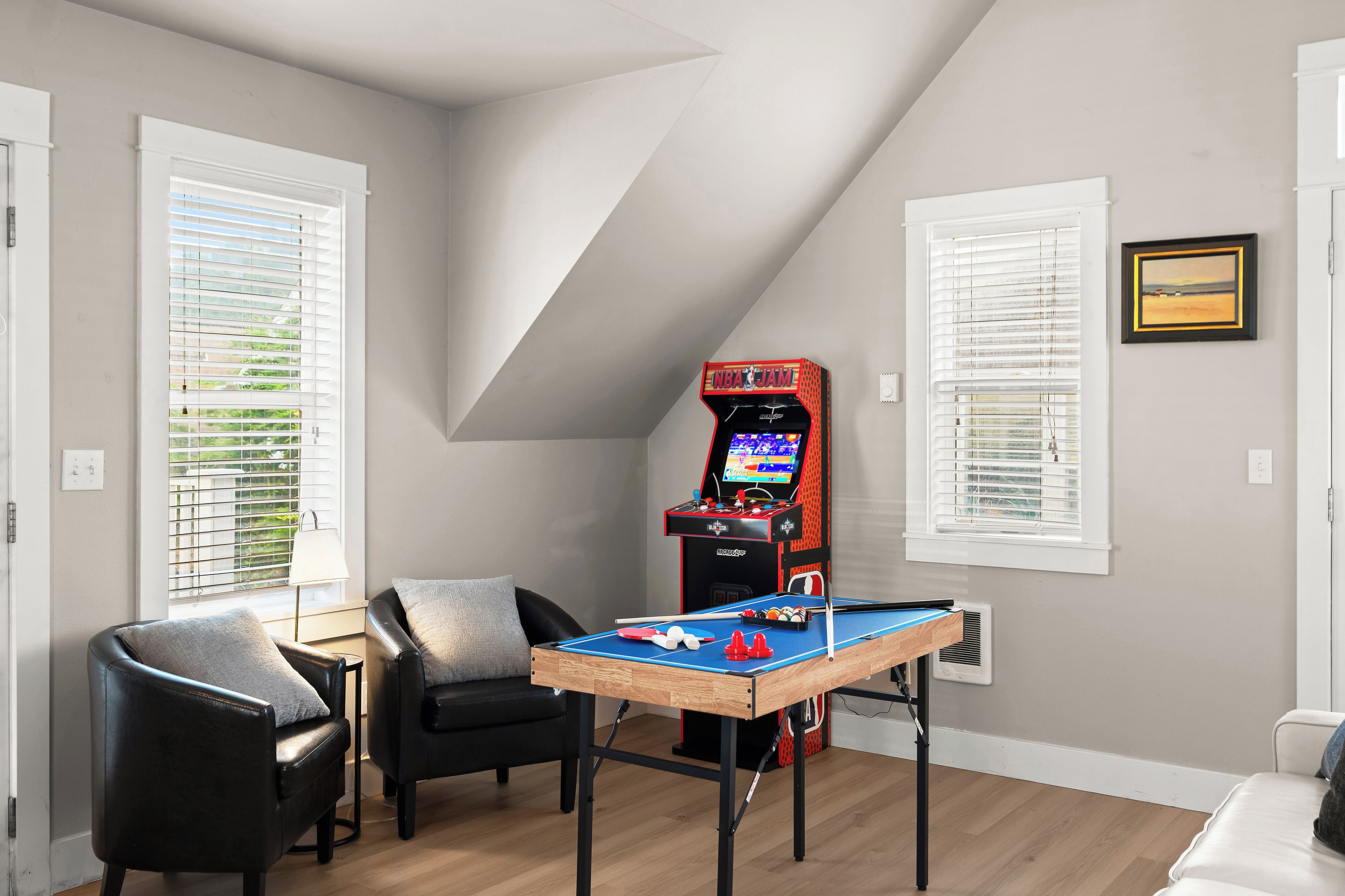 A room with a pool table, a gaming console, and a couch.