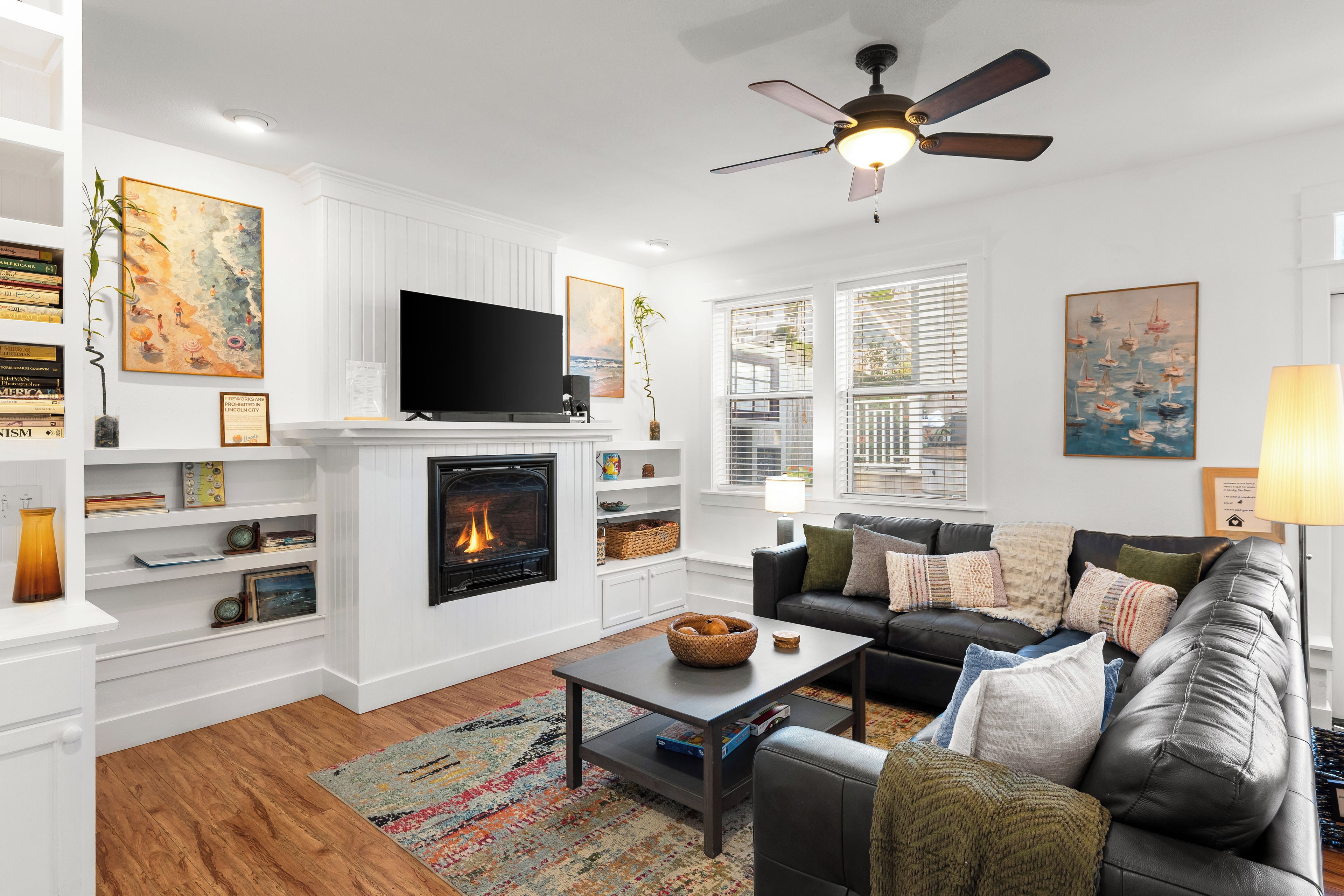 A living room with a fireplace, a television, a sofa, and a ceiling fan.