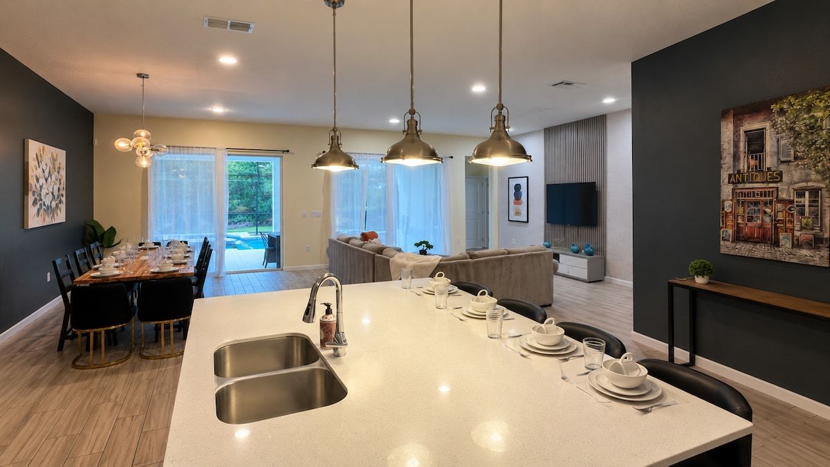 A modern kitchen with a central island, pendant lighting, and a dining area with a curved bench.