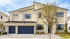 A two-story residential building with a garage, a stone facade, and a well-maintained lawn. - Lakeview 15BR Mansion • Pool, Cinema, Games Room (Kissimmee)