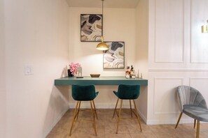 Een moderne keuken met een blauwgroen aanrecht, twee barkrukken, een hanglamp en decoratieve objecten.