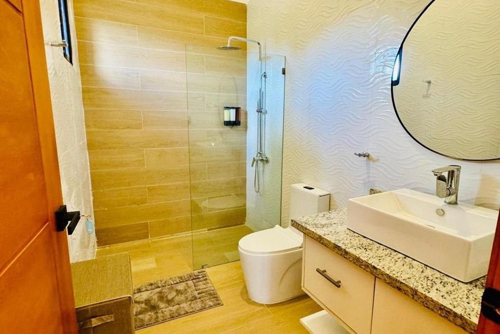 A bathroom with a glass shower enclosure, a white toilet, a sink with a mirror, and a towel rack.