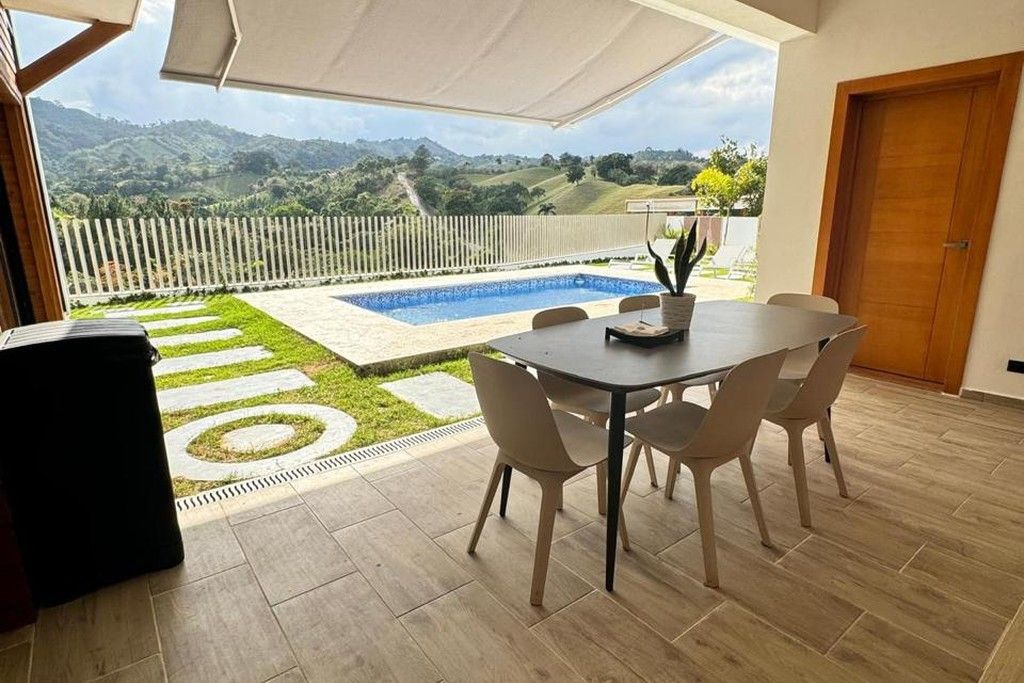Un patio con piscina, mobiliario exterior y vistas a las colinas.