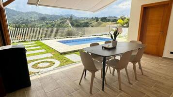 Un patio con piscina, mobiliario exterior y vistas a las colinas.