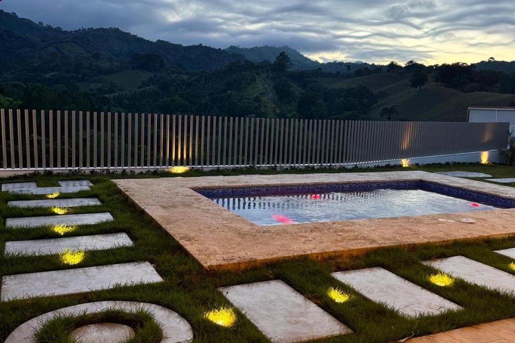 Un jardín ajardinado con piscina, escalones de piedra y valla de madera.