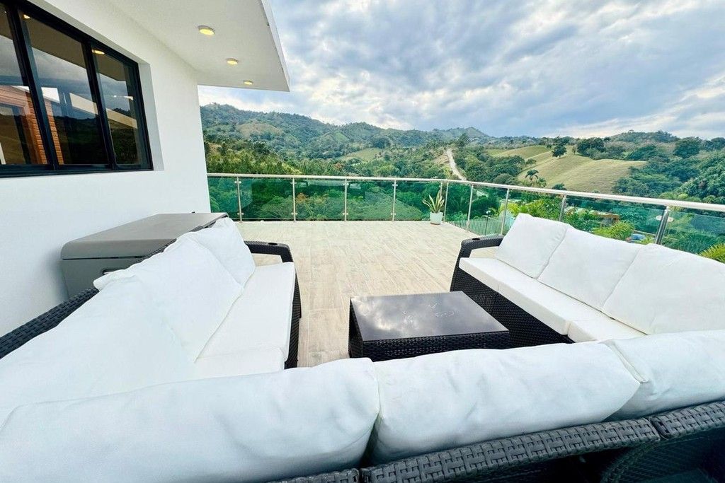 Un balcón con sofá y mesa, con vistas a un paisaje montañoso.