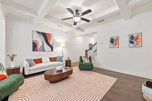 A modern living room with a white sofa, a green armchair, a round coffee table, and a patterned rug. - Modern 3BR Townhome Near Stonecrest (Lithonia)