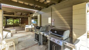 Een buitenbarbecueplaats met twee barbecues, een gasfornuis en een spoelbak.