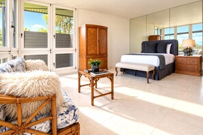 Quarto com cama, mesa de cabeceira, armário de madeira, cadeira de vime e janela com persianas.