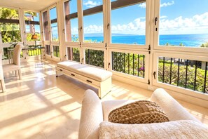 Quarto com uma janela grande que oferece uma vista panorâmica, um banco e uma mesa com abajur.