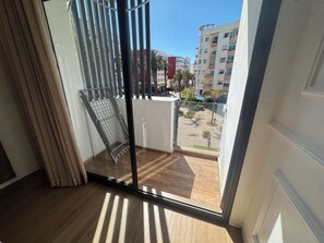 A room with a sliding glass door leading to a balcony with a view of a residential area and a building with balconies. - New Luxury 3-Bedroom Apartment (Casablanca)