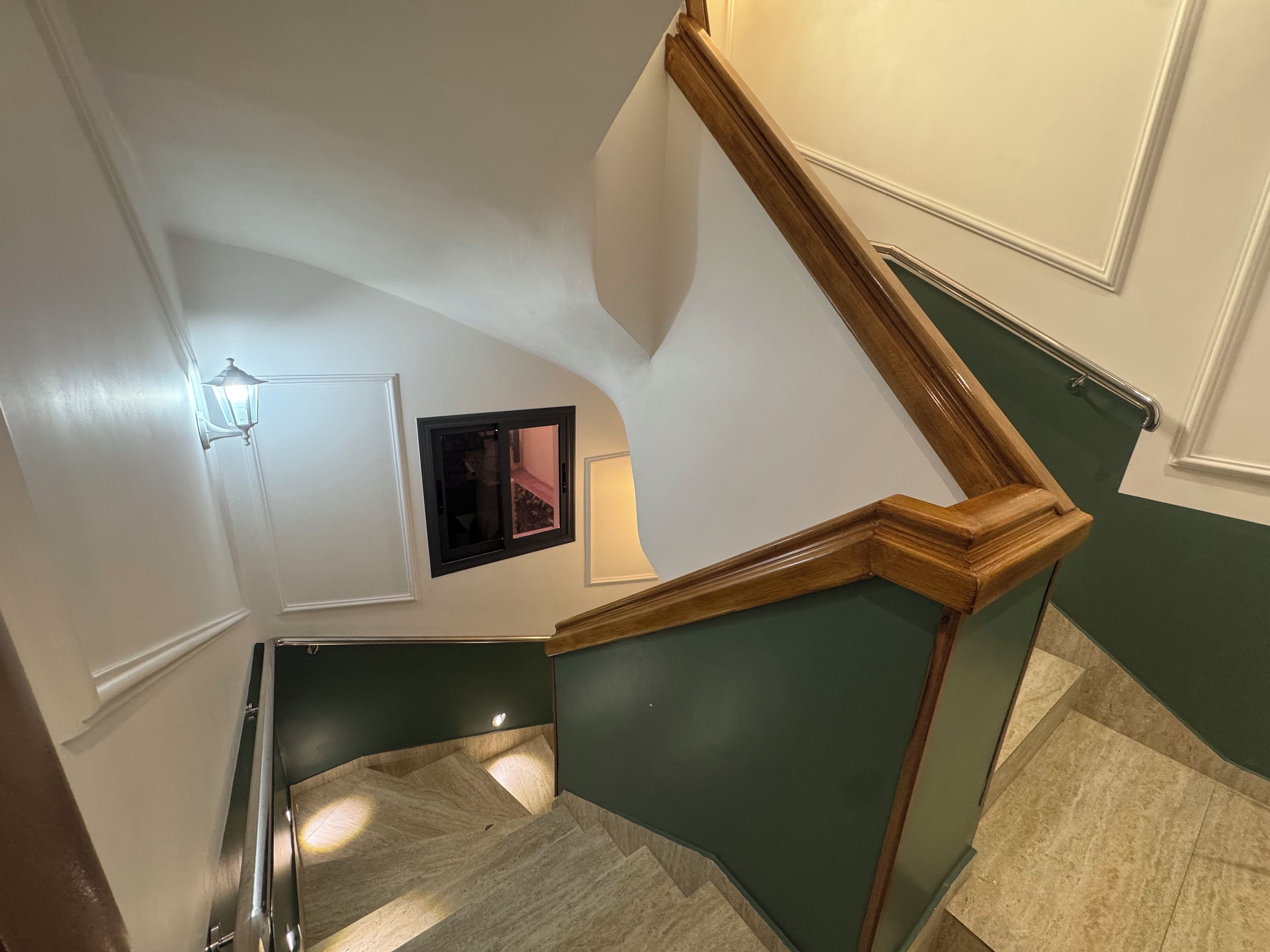 A staircase with a wooden handrail and a wall-mounted light fixture.