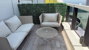 A balcony with a sofa, a chair, and a small table.