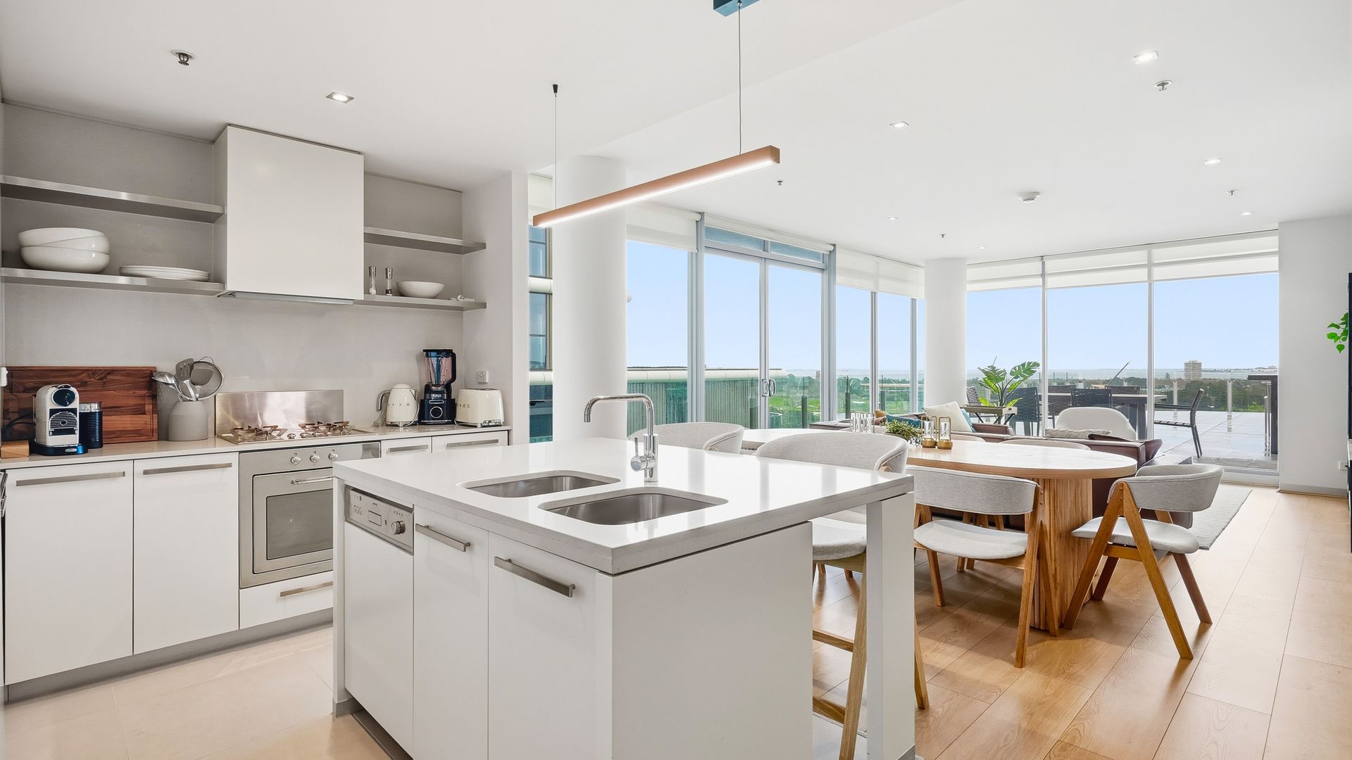 A modern kitchen with a central island, built-in appliances, and a dining area with a view.