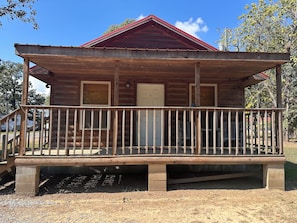 A wooden cabin with a porch, a door, and a window.