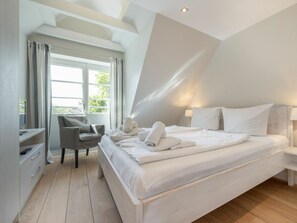 A modern bedroom with a large bed, a desk, and a chair. - Holiday Home With 4 Bedrooms (Sylt)