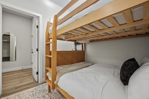 A bunk bed with a wooden frame and white bedding, a mirror on the left, and a patterned rug on the floor. - Montane | Slope-Side | Hot Tub | Resort Access (Panorama)