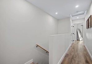 A modern interior with a wooden staircase, white walls, and a wooden floor.