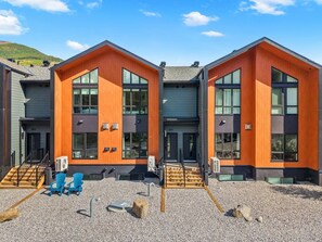 A modern building with a two-story structure, large windows, and a gravel driveway.