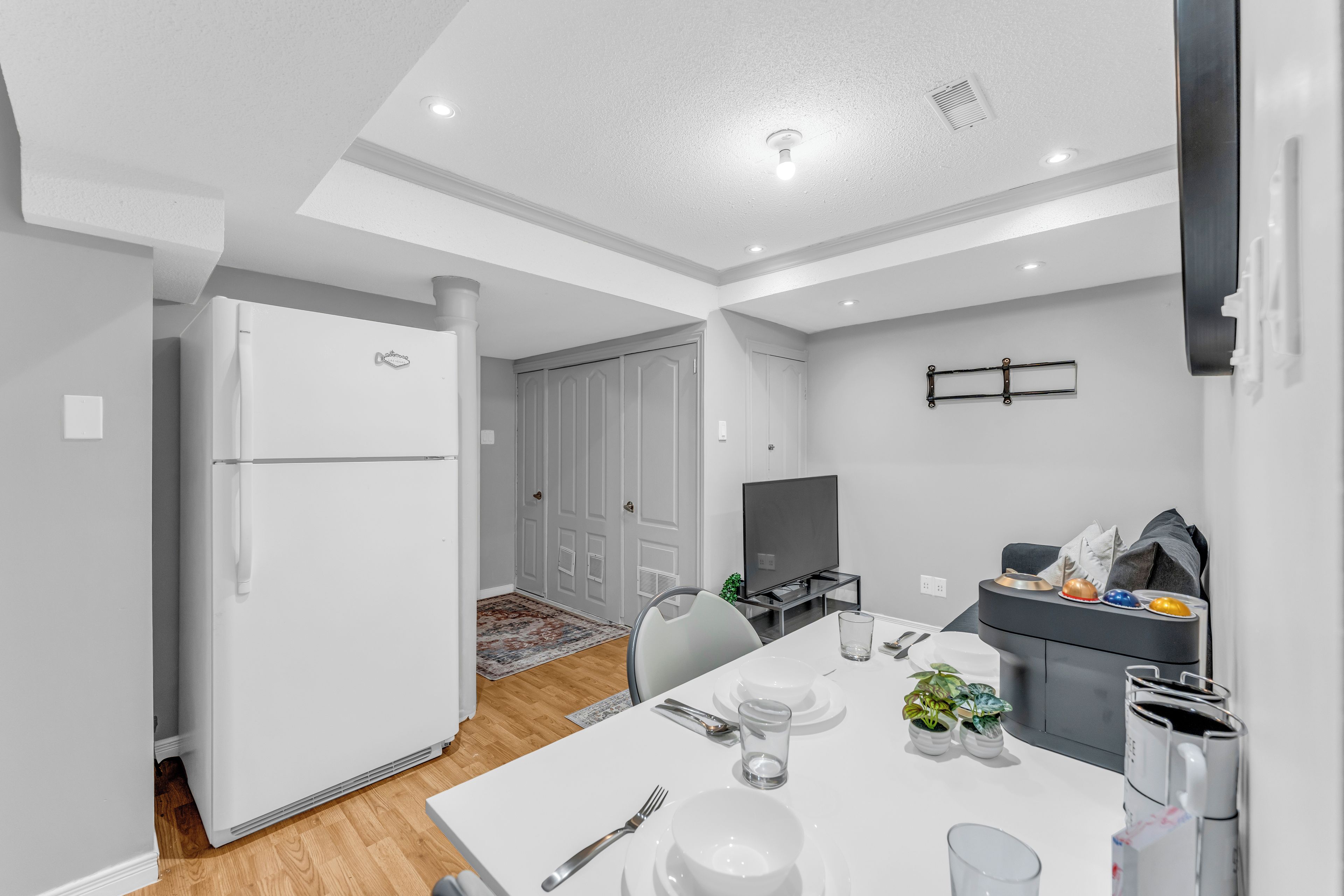A modern kitchen with a built-in oven, a dining area with a table set for two, and a television on a stand.