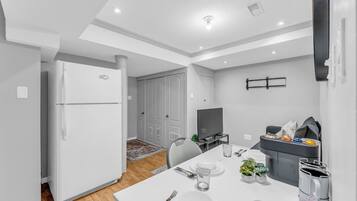 A modern kitchen with a built-in oven, a dining area with a table set for two, and a television on a stand.