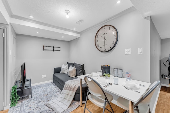 Una sala de estar moderna con un sofá, una mesa de centro y un comedor con sillas y un reloj en la pared.
