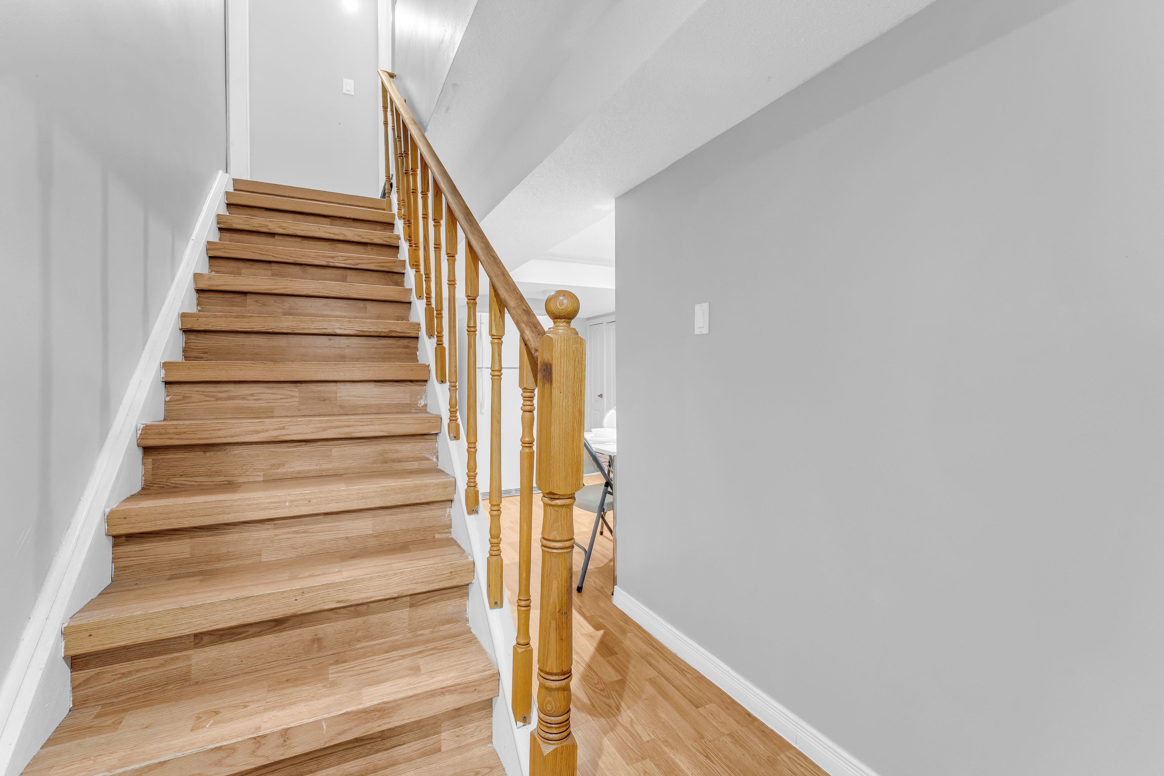 Eine Holztreppe mit Geländer, weißen Wänden und einem Holzboden.