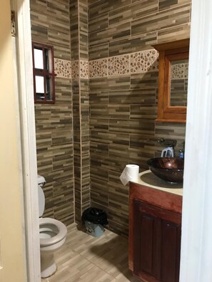Une salle de bain comprenant des toilettes, un lavabo et un espace douche.