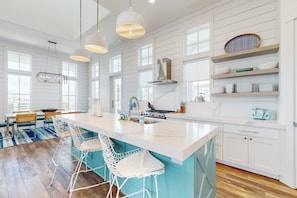 A modern kitchen with a large island, bar stools, and pendant lighting. - Palmilla Beach Resort-142 Sunset Avenue (Port Aransas)