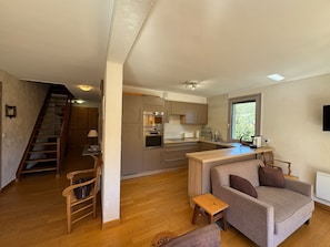 A modern kitchen with built-in appliances, a dining area with a sofa, and a staircase leading to another level. - Duplex 8 pers - Vue montagne - Balcon sud - Pistes à 100 m (Vars)