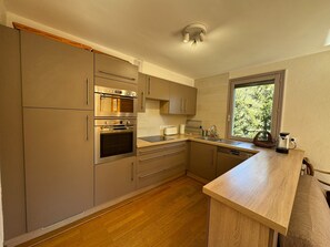 A modern kitchen with stainless steel appliances, wooden flooring, and a window providing natural light. - Duplex 8 pers - Vue montagne - Balcon sud - Pistes à 100 m (Vars)